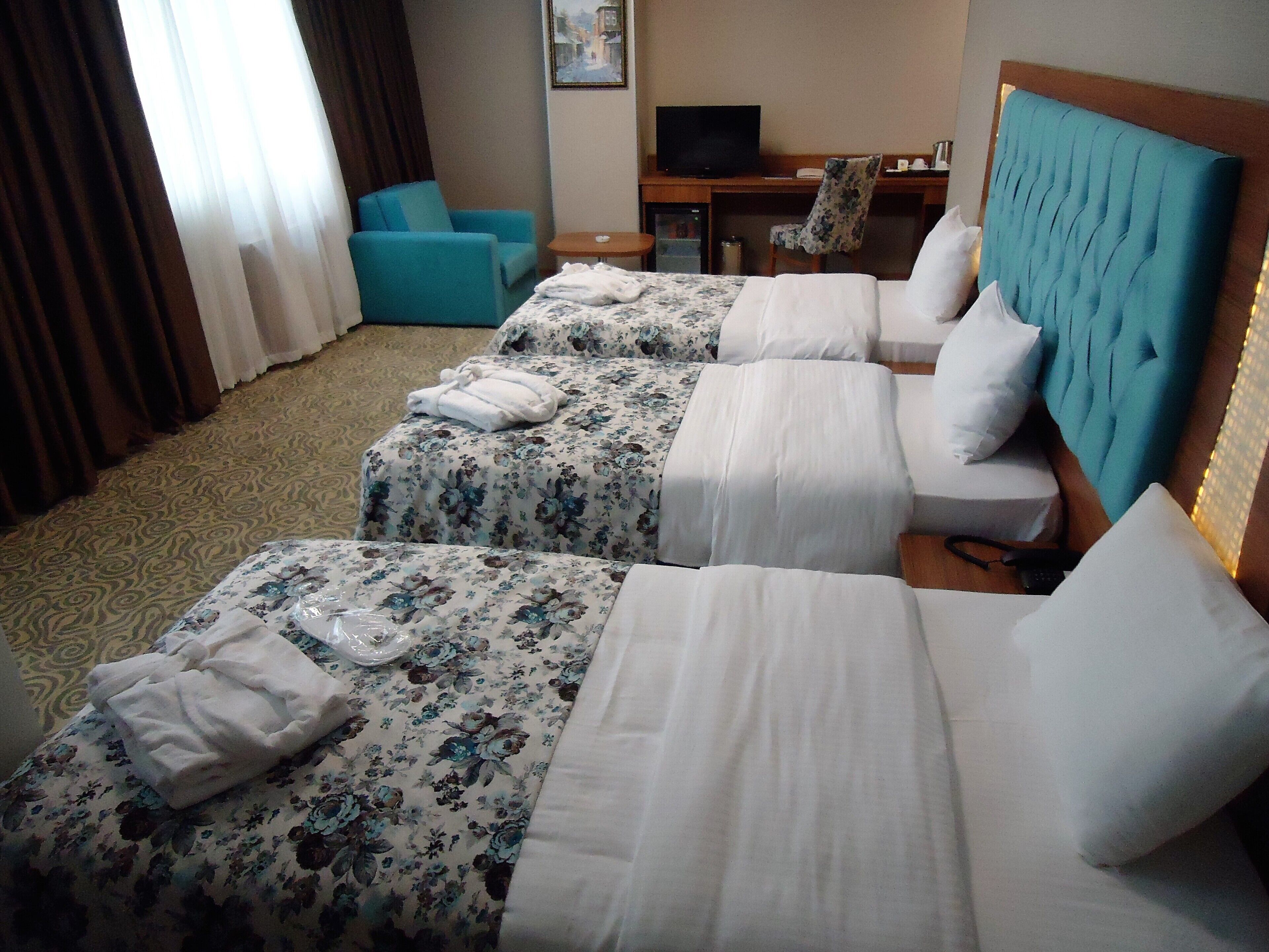 A hotel room with two beds, a desk, a television, and a chair.