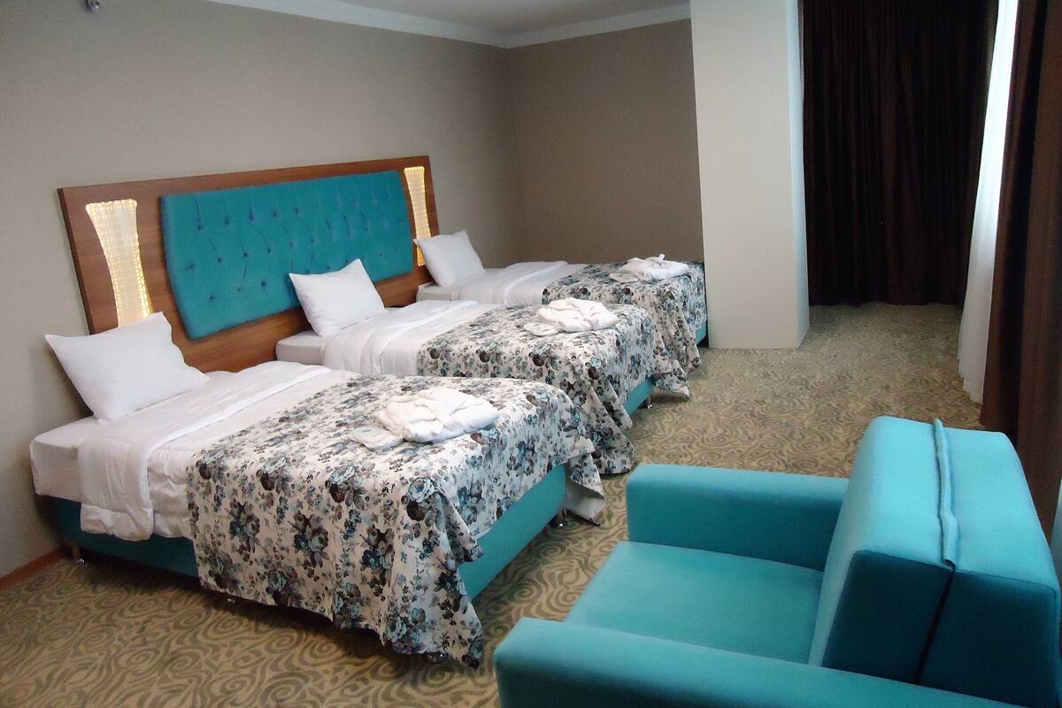 A hotel room with two beds, a sofa, and a large window.