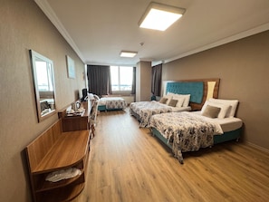 Habitación cuádruple Deluxe | Ropa de cama de alta calidad, artículos del minibar gratis y escritorio