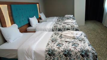 Habitación de hotel con dos camas, cada una con cabecera, ropa de cama blanca y colchas con estampado floral.