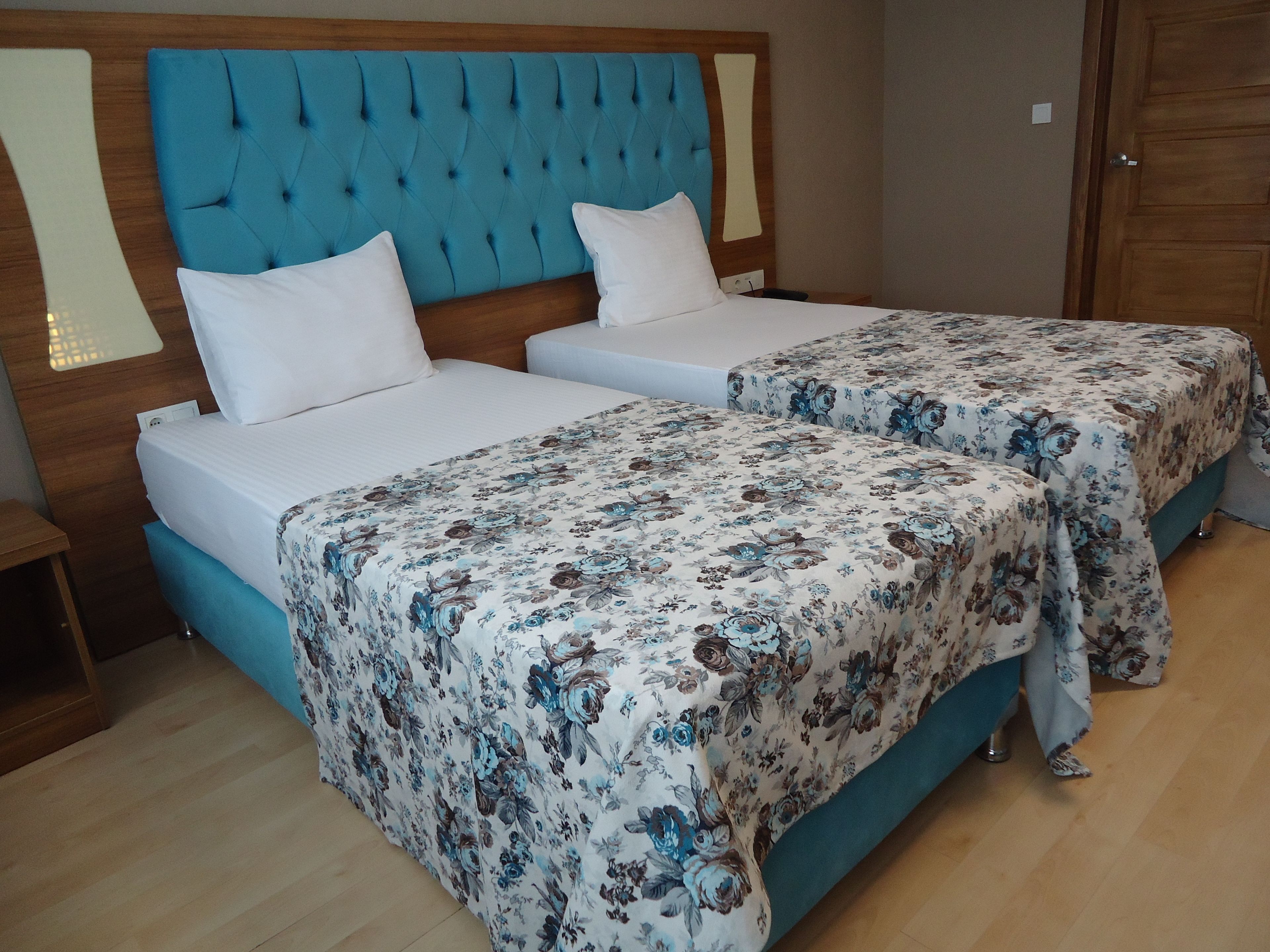A hotel room with two beds, each with a floral bedspread and white pillows.