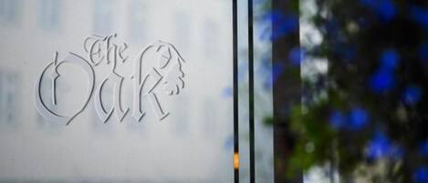 Una puerta de cristal con un logotipo que incluye el texto 'The OAK' y un árbol estilizado.