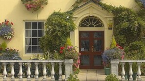 Un edificio con fachada simétrica, una entrada central con ventanal y jardineras en los alféizares de las ventanas.