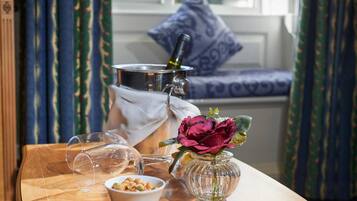 Une table en bois sur laquelle se trouvent une bouteille de vin, un verre, un bol de noix et un vase avec une fleur.