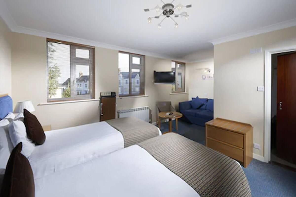 A hotel room with two beds, a TV, a chair, and a small table.