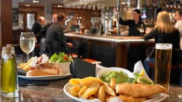 Eine Bar mit einer Theke, Biergläsern und einer Speisenplatte, darunter Fish and Chips.