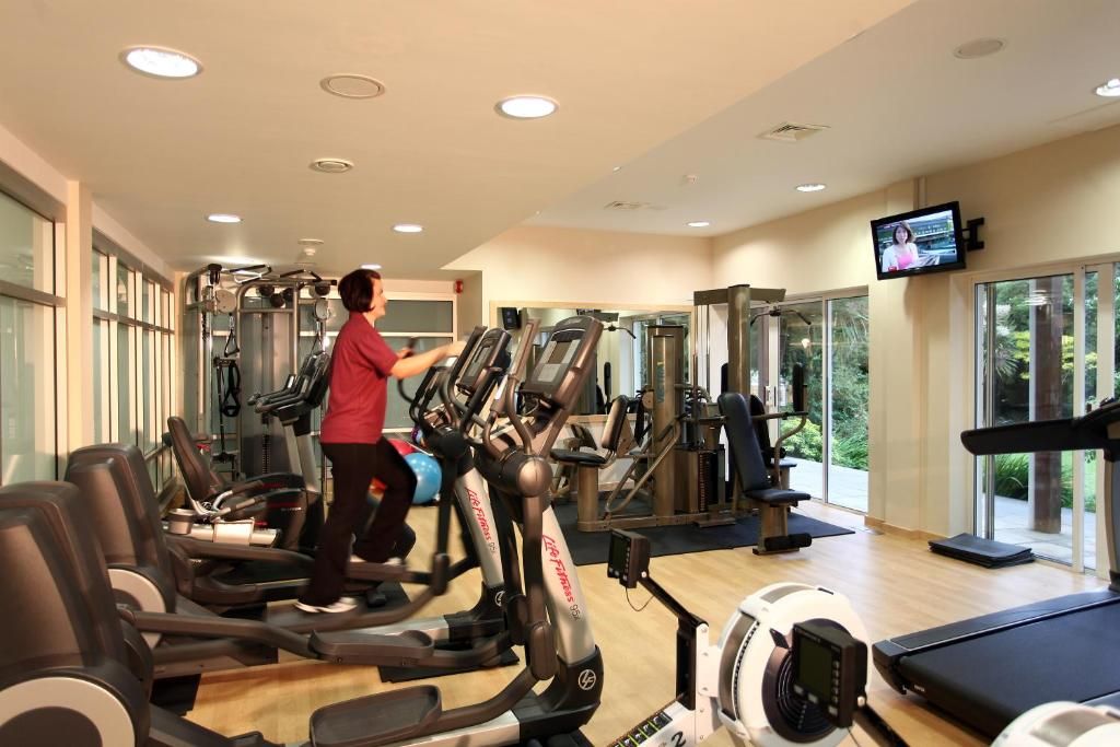 Un gimnasio con cintas de correr, elípticas y equipo de pesas.