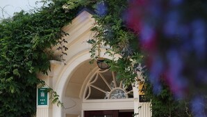 Entrada de hotel con fachada blanca, un arco de entrada y un letrero que indica una calificación de 3 estrellas.