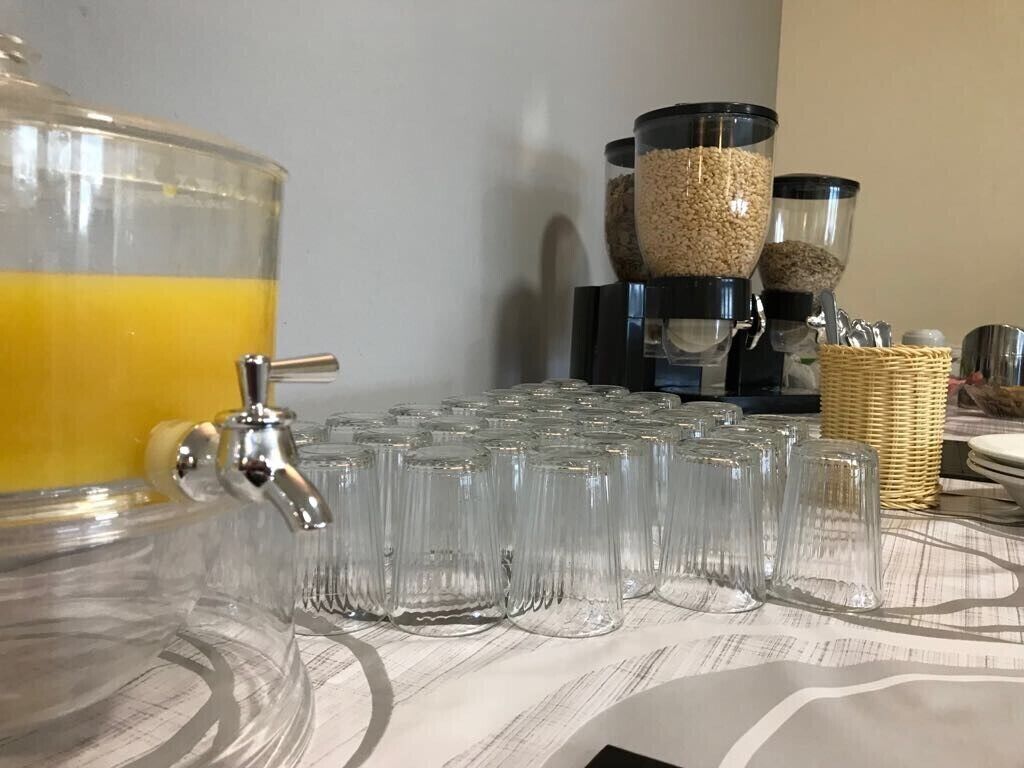 A beverage dispenser with a tap and multiple glasses, a coffee maker, and a basket of utensils.