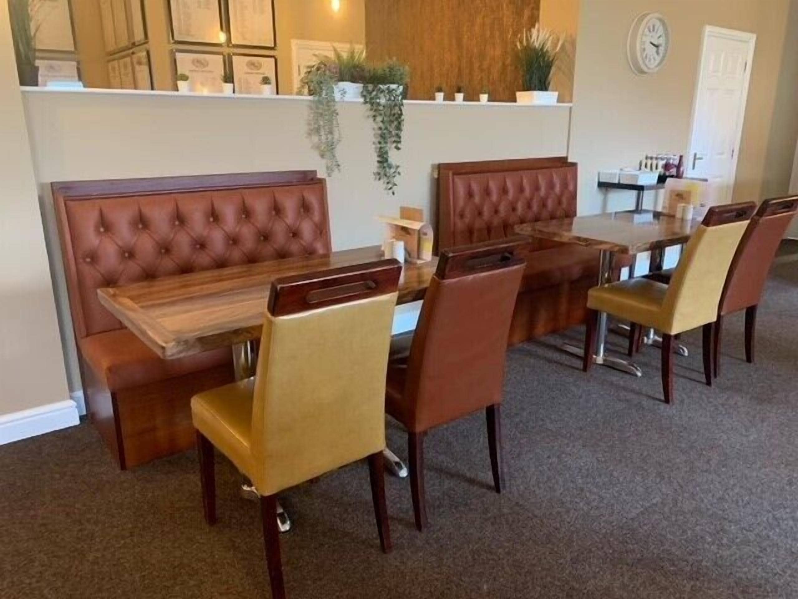 Een eetgedeelte met een houten tafel, beklede stoelen, een bank en een klok aan de muur.