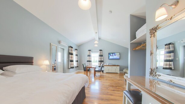 A modern hotel room with a large bed, a desk, and a mirror. - Silverstone Golf Club & Hotel (Buckingham)