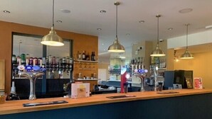 A bar area with a counter, hanging pendant lights, and shelves with bottles. - Silverstone Golf Club & Hotel (Buckingham)