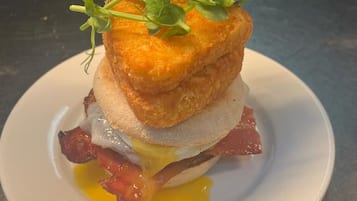 A breakfast dish with a fried egg, bacon, and a piece of bread, garnished with greens.