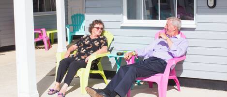 Two people sitting on colorful chairs outside a building with a number sign indicating a room number.