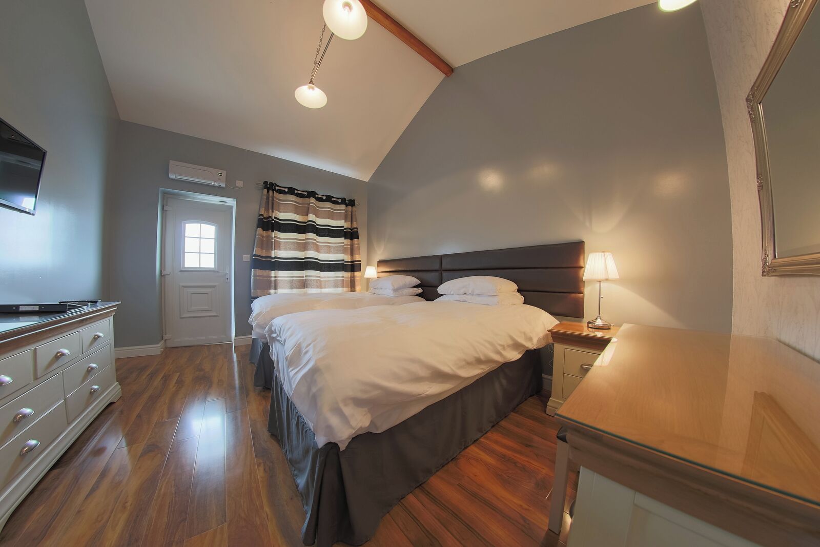 A bedroom with a large bed, bedside tables, a dresser, and a ceiling light fixture.