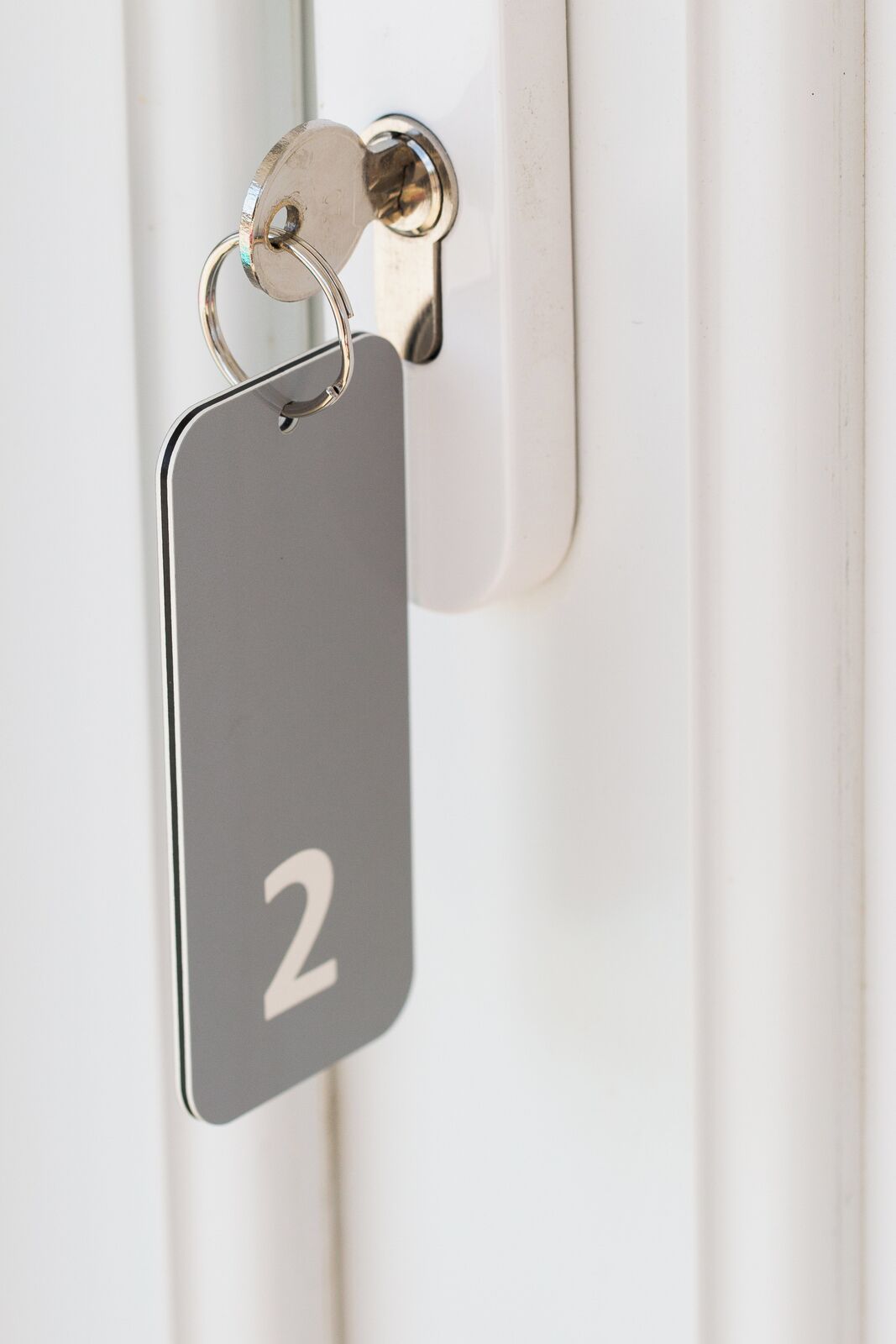 A metallic key tag with the number 2 attached to a door handle.