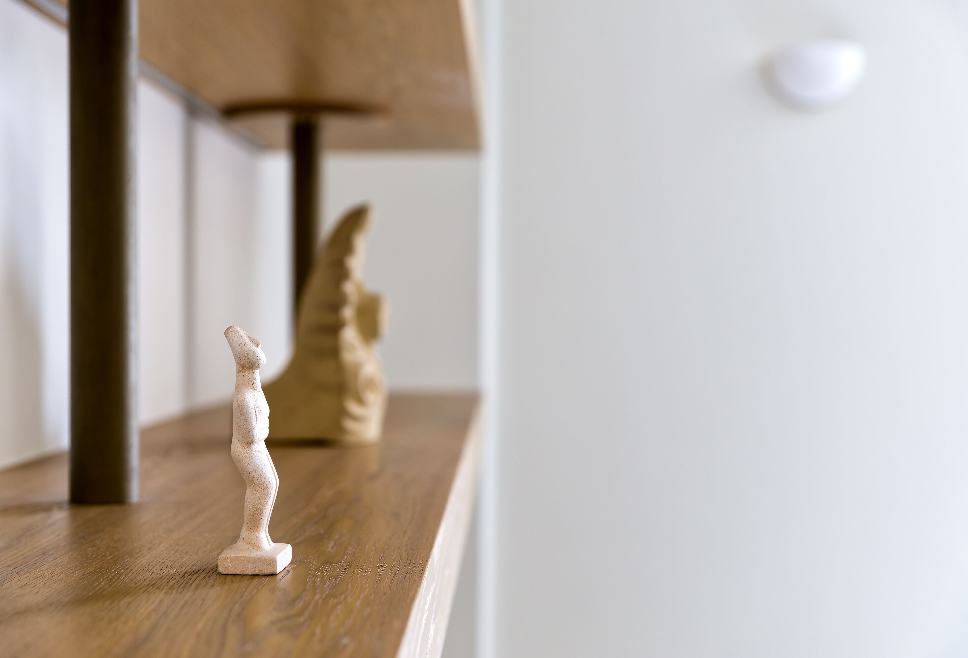 A wooden shelf with a small figurine and a decorative item.