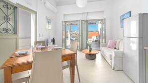 A modern kitchen with a dining area, a sofa, and a view through the open door. - Belvedere Andros (Andros)