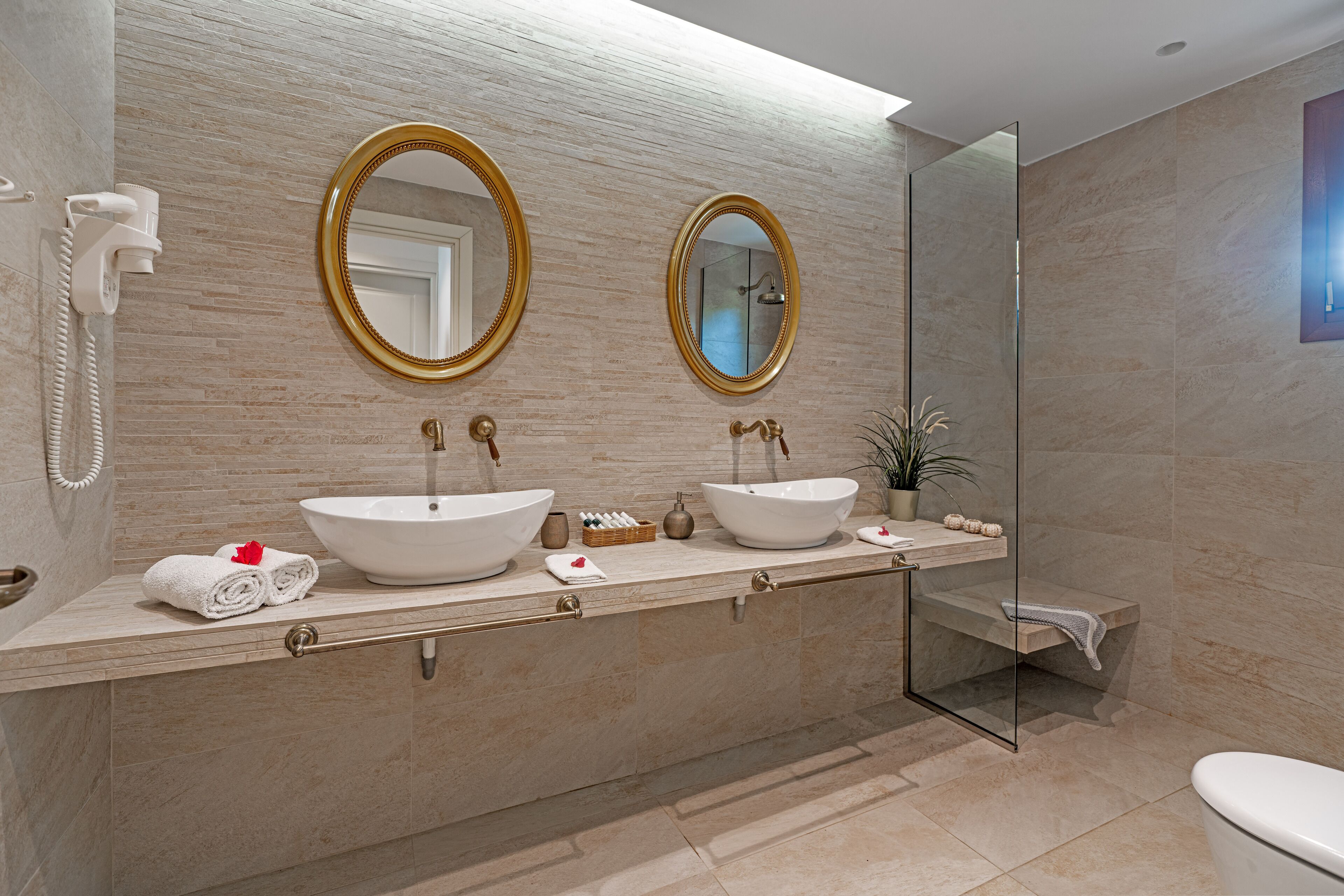 A modern bathroom with two large sinks, a glass shower enclosure, and a built-in phone.
