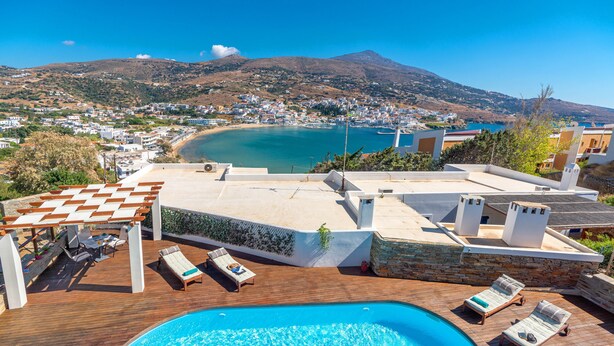 A rooftop pool with lounge chairs and a view of a coastal town and mountains. - Belvedere Andros (Andros)