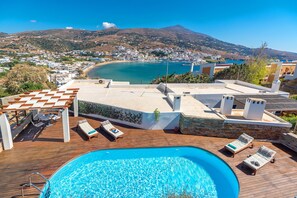 A rooftop pool with lounge chairs and a view of a coastal town and mountains. - Belvedere Andros (Andros)