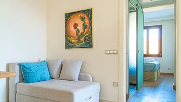 Ein Wohnzimmer mit einem beigen Sofa, einem blauen Kissen und einem Bild an der Wand.