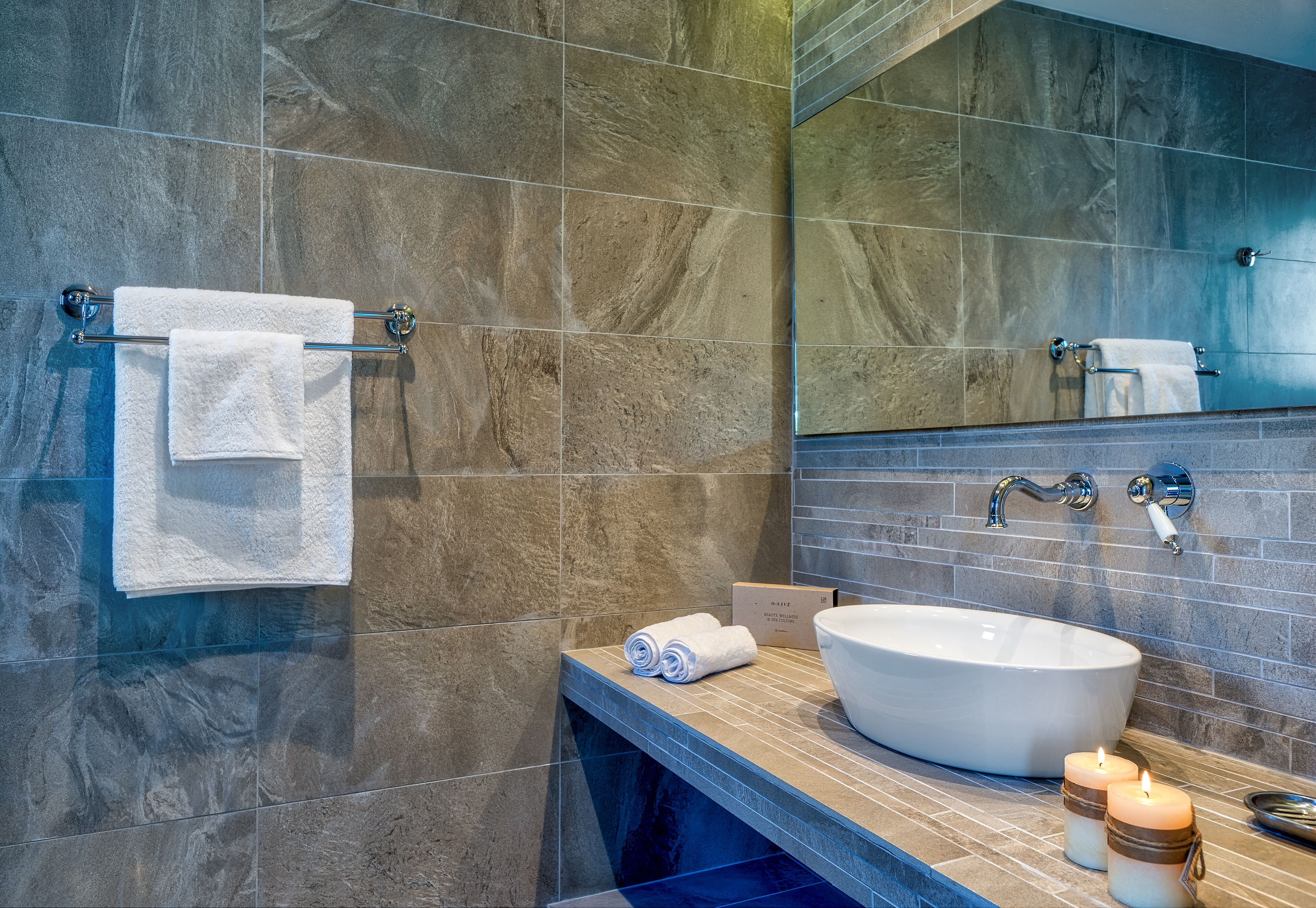 A bathroom with a large oval sink, two towels on a rack, and a mirror above the sink.