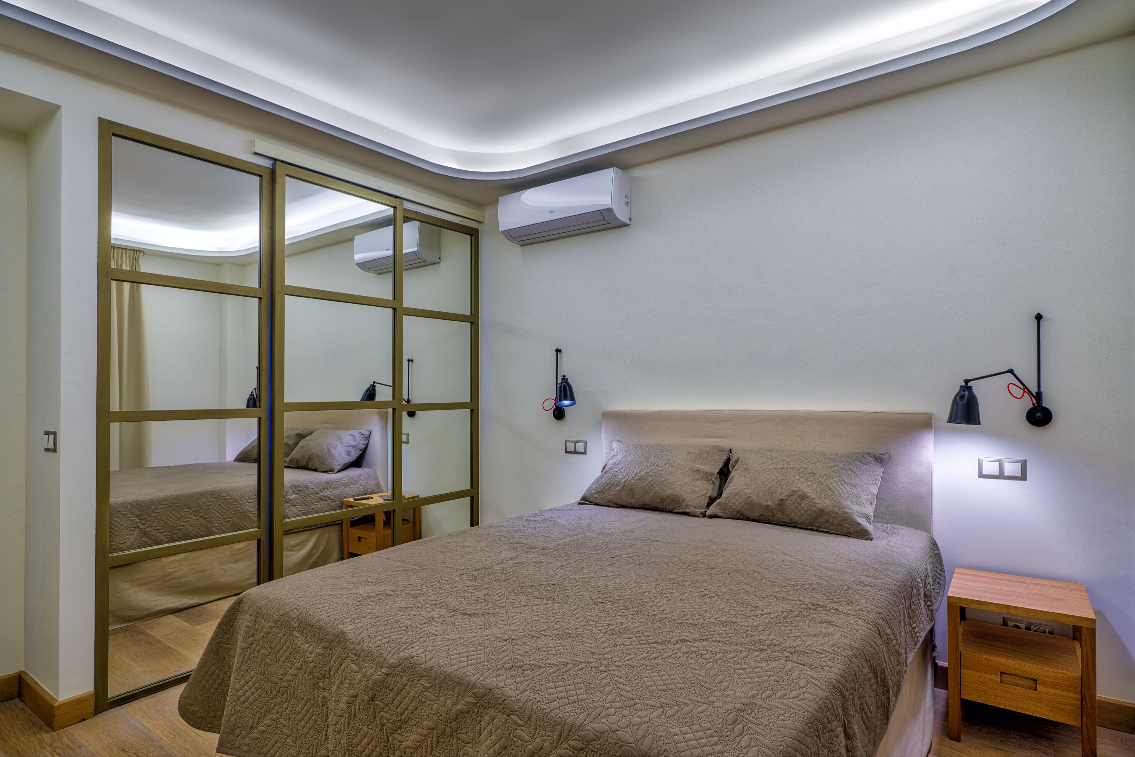 A bedroom with a bed, a nightstand, a wall-mounted air conditioner, and a sliding door closet.