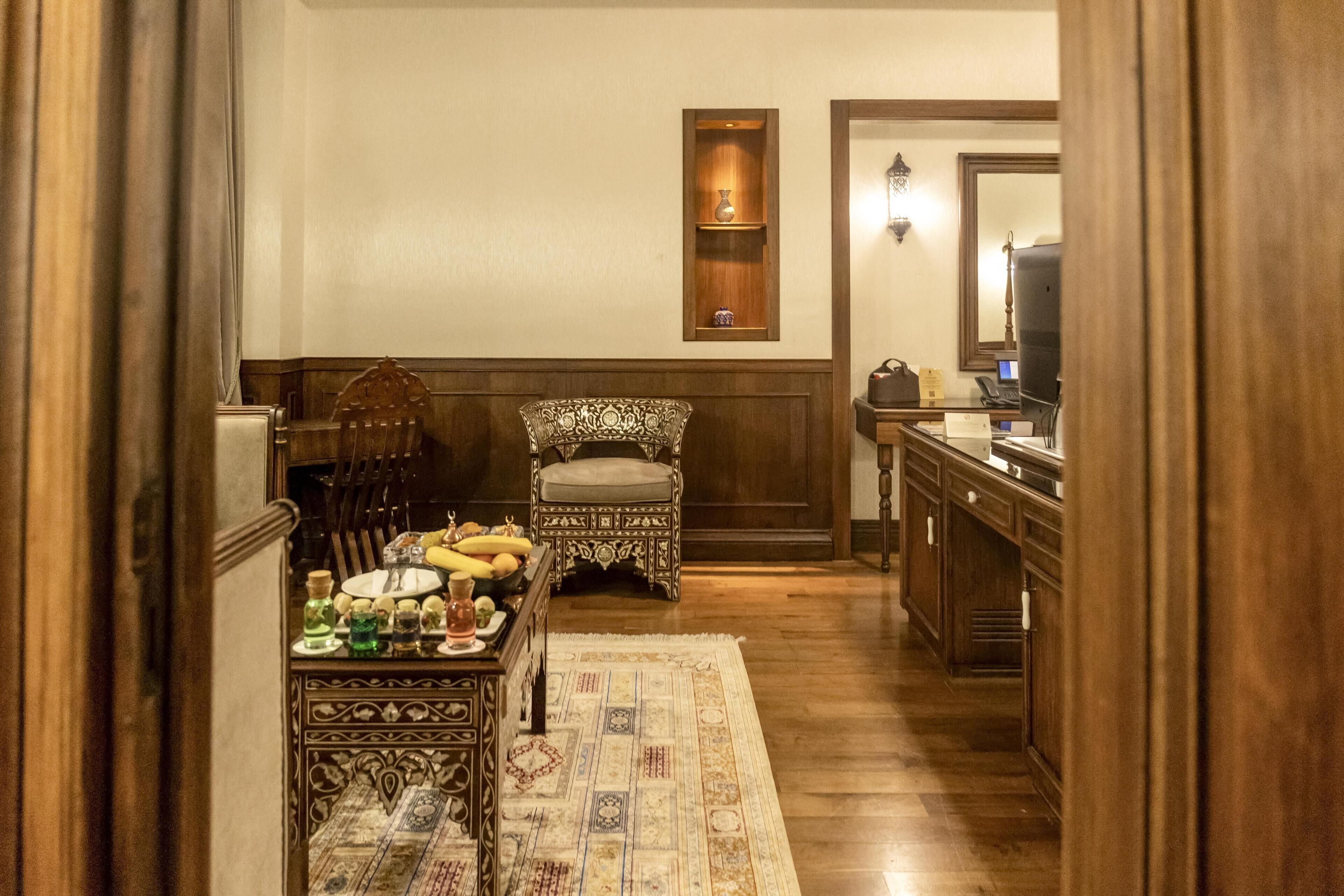 Un coin repas traditionnel avec une table en bois dressée pour quatre personnes, un tapis à motifs et une chaise décorative.