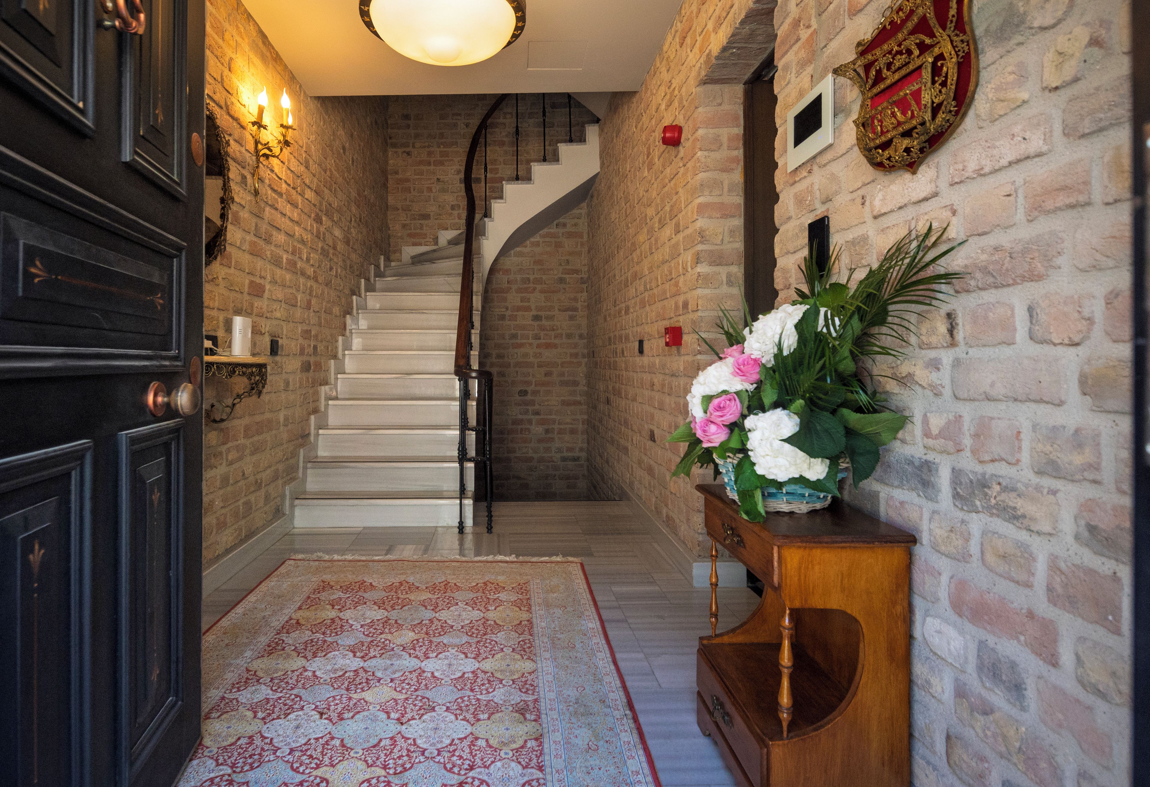 A staircase with a white railing leading to a landing, a dark wooden door, and a wall-mounted light fixture.