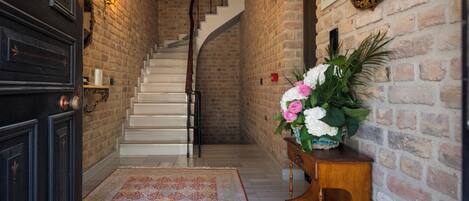 A staircase with a white railing leading to a landing, a dark wooden door, and a wall-mounted light fixture.