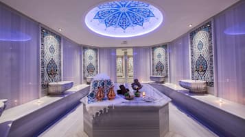 Relax in a spacious bathroom with a central seating area, ornate ceiling design, and two sinks with matching basins.