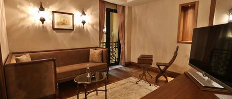 Una sala de estar con un sofá, una mesa de centro, un televisor y una mesita de madera.