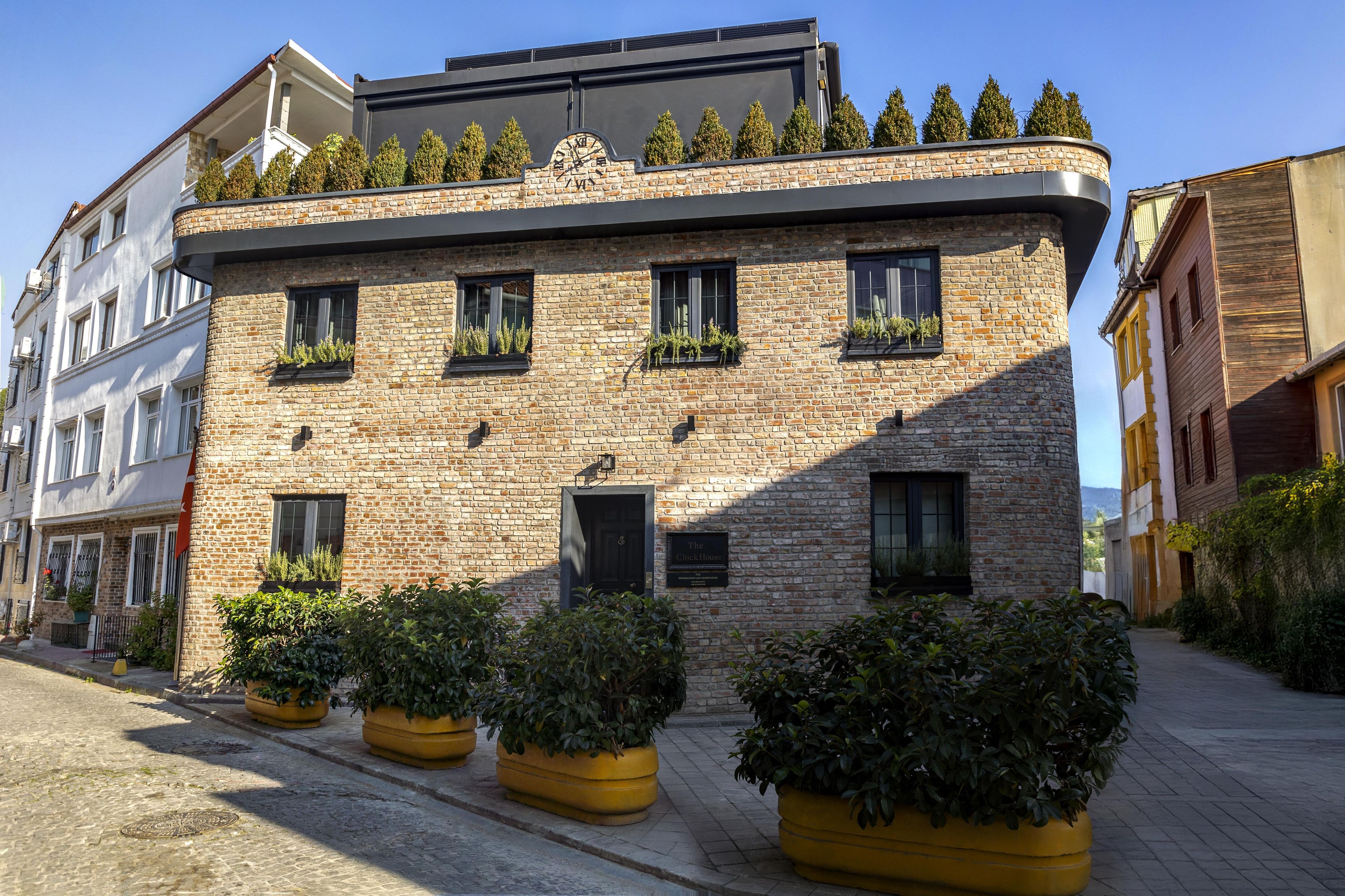 A brick building with multiple windows, potted plants, and a clock on the facade.