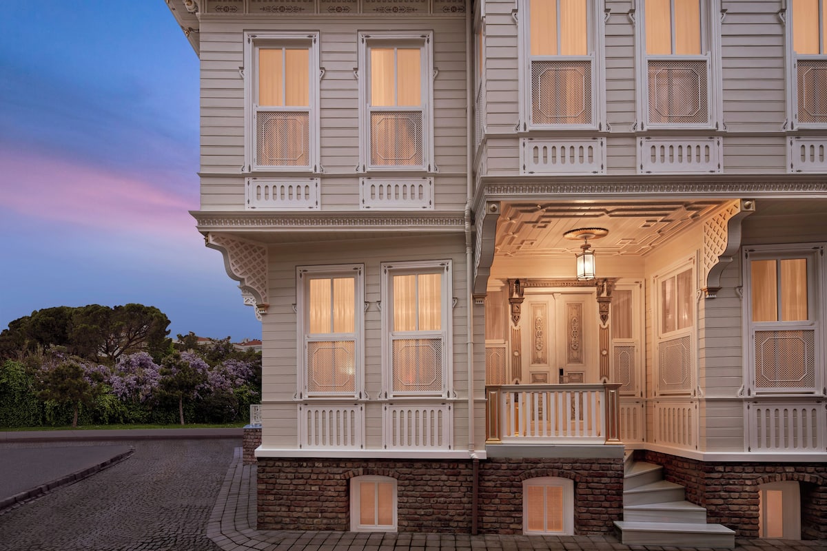 A two-story building with a porch, multiple windows, and a stone foundation.