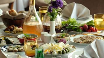 A table set for a meal with various dishes, a bottle of liquid, and a vase with flowers.