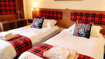 A hotel room with two beds, each with a red plaid bedspread and matching pillows.
