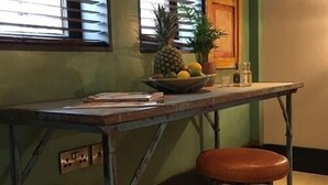 A kitchen with a wooden table, a bowl of fruit, and a potted plant. - Charter House (Newport)