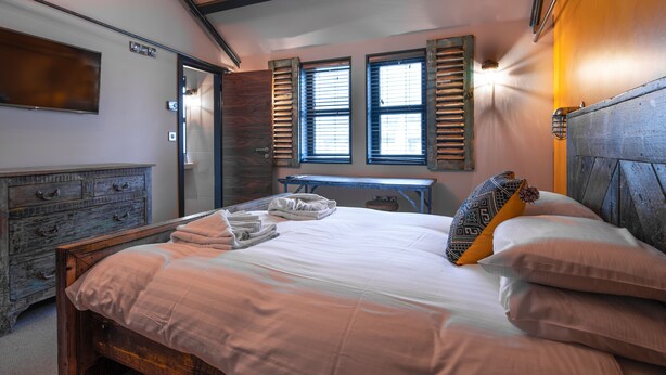 A bedroom with a bed, wooden headboard, a dresser, and a desk. - Charter House (Newport)