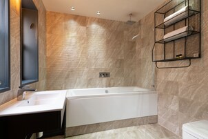 Un baño moderno con bañera, lavamanos y toallero.