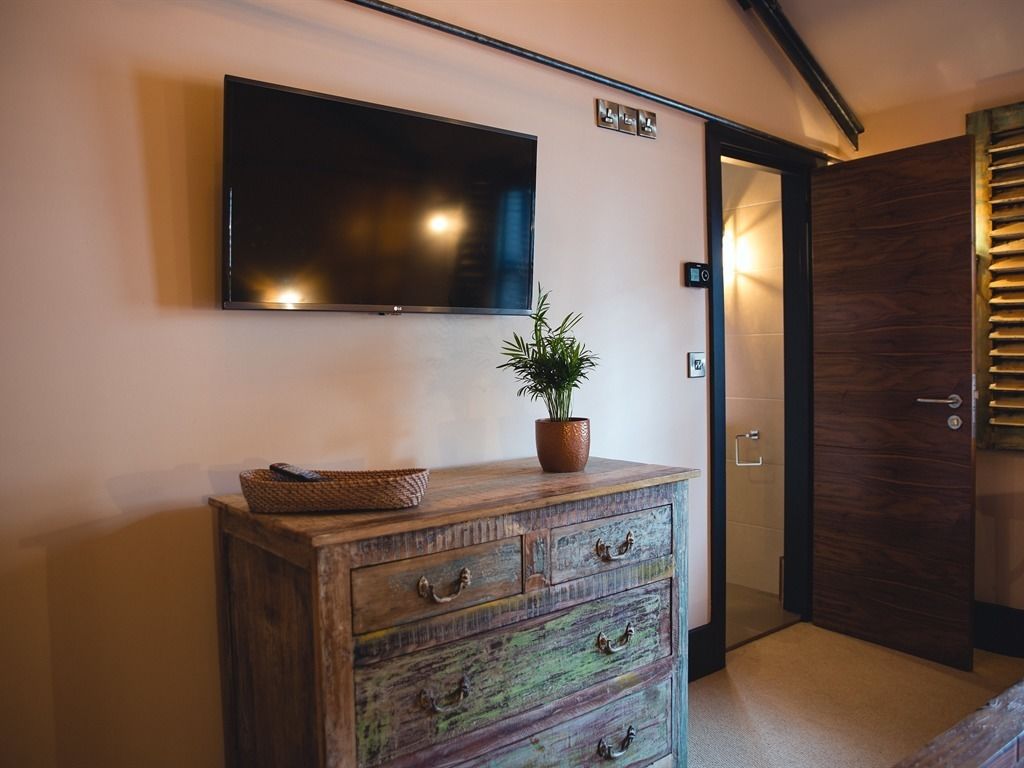 A wooden dresser with drawers and a flat-screen TV mounted on the wall.