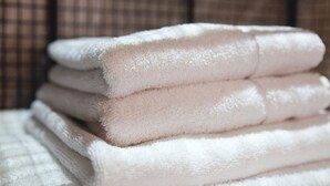 A stack of white towels on a bed with a checkered pattern in the background. - Charter House (Newport)