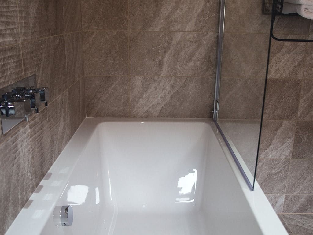 Une salle de bain moderne dotée d’une grande baignoire, d’un espace douche et d’un porte-serviettes fixé au mur.