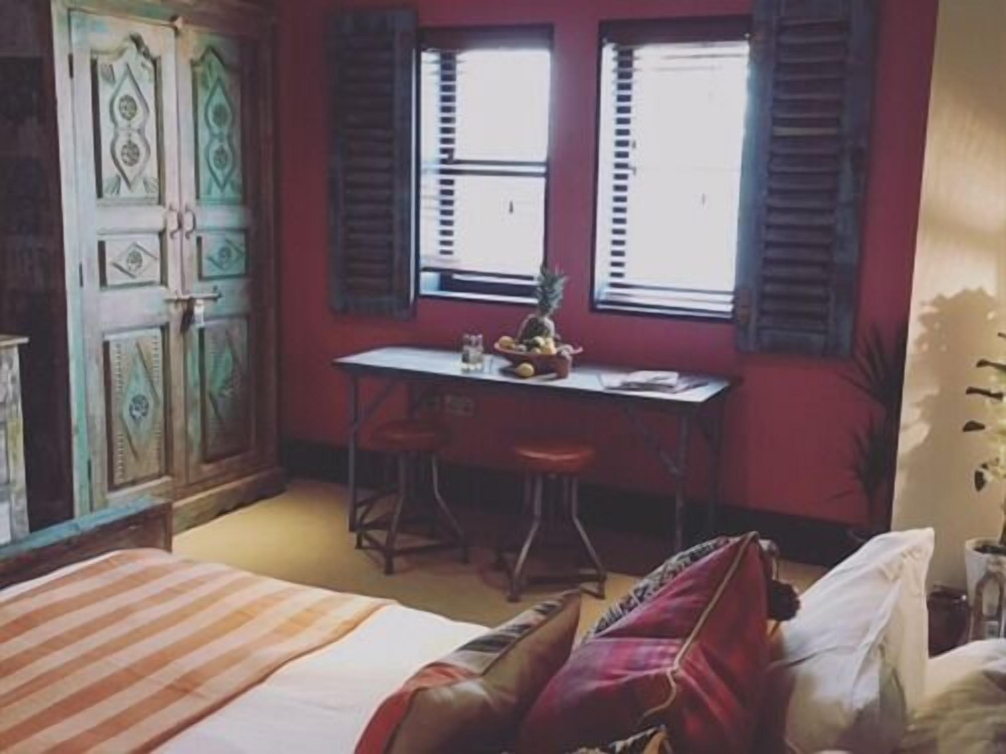 A room with a bed, a desk, and a window with shutters.
