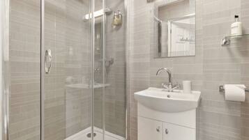 A modern bathroom with a glass-enclosed shower, a white sink, and a mirror above it.