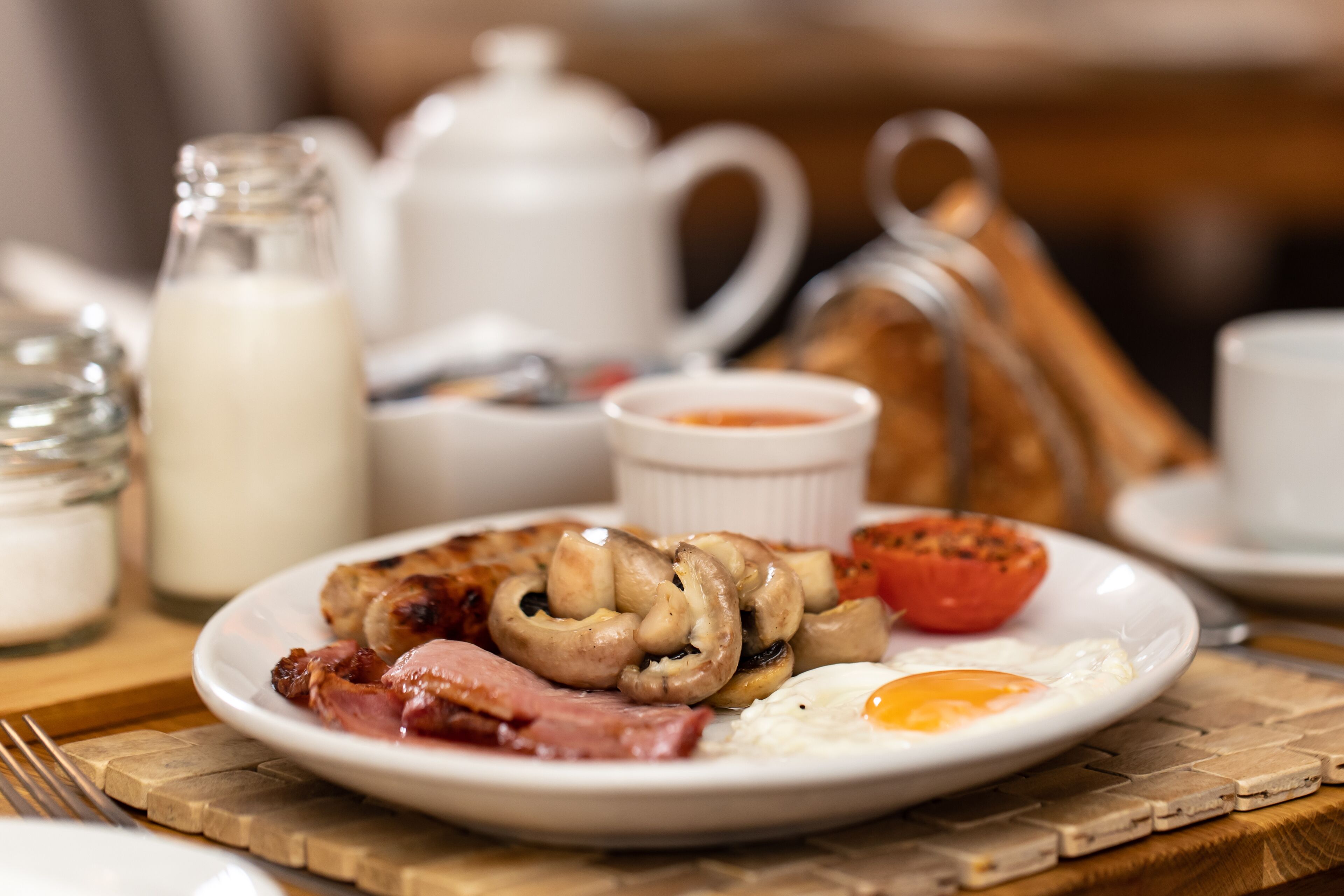 A breakfast plate with eggs, bacon, mushrooms, and a tomato.