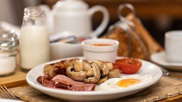 A breakfast plate with eggs, bacon, mushrooms, and a tomato.
