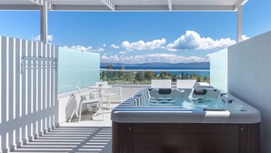 Une terrasse sur le toit avec un jacuzzi, un espace salon et une vue sur la mer.