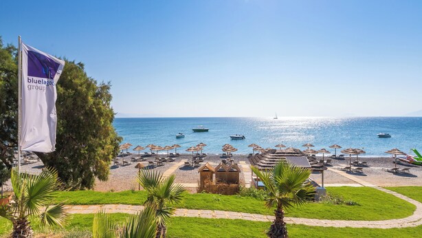 Une plage avec des parasols, des chaises longues et un drapeau.