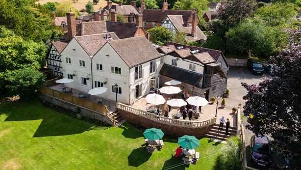 A large, traditional building with multiple windows and a covered patio area with outdoor seating. - The Manor at Abberley (Worcester)